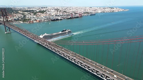 A bird's eye view of the 25 de Abril Bridge (Portuguese: Ponte 25 de Abril) across the Tagus river with a sailing cruise ship, Lisbon photo