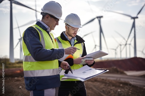 Diverse Team of Specialists Use Tablet Computer on Construction Site. Real Estate windmill farm Project with Civil Engineer, Architect, Business Investor and General Worker Discussing Plan Detail