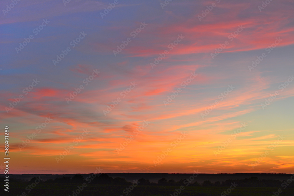 A stunning sunset with orange, yellow and red colors on a blue sky and clouds 