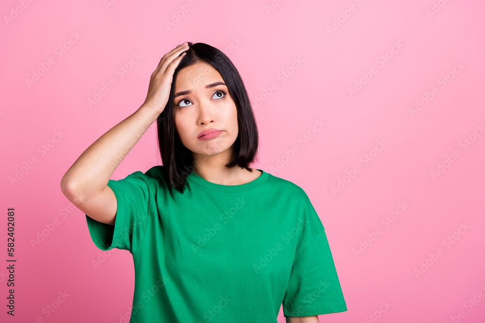 Photo of pleasant cute girl with bob hairdo dressed green t-shirt hold arm on head look up empty space isolated on pink color background Photo of pleasant cute girl with bob hairdo dressed green t-shirt hold arm on head look up empty space isolated on pink color background
