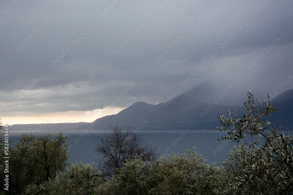 Mountains in the fog above the sea bay in the background. In the foreground is a park. Italian coastal landscape
