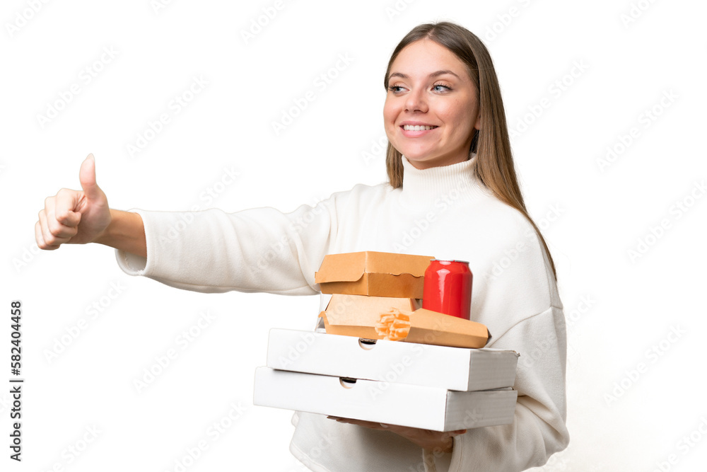 Young beautiful blonde woman holding takeaway food over isolated background giving a thumbs up gesture Young beautiful blonde woman holding takeaway food over isolated background giving a thumbs up gesture