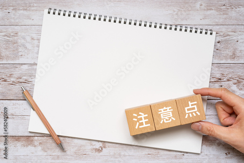注意点と書かれたブロック、ノート、ペン、手