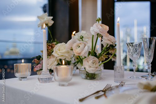 Banquet table decorated with plates, cutlery, candles, glasses and flower arrangements