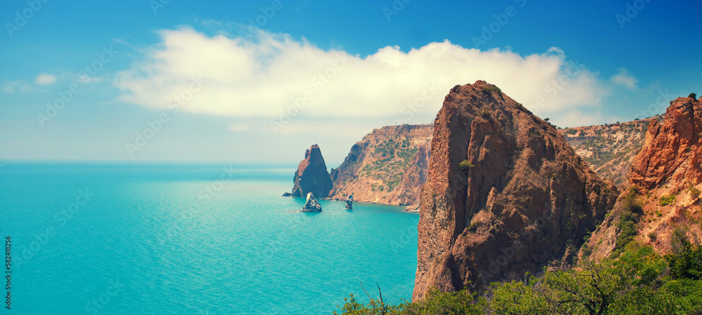 Rocky seascape on a sunny day. View of the sea coast from the mountain. Horizontal banner