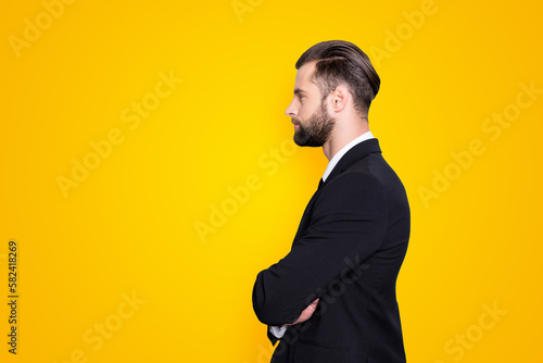 Profile side view portrait with copy space, empty place for advertisement of attractive, concentrated, stylish, virile man with modern hairstyle, holding arms crossed, isolated on grey background photo