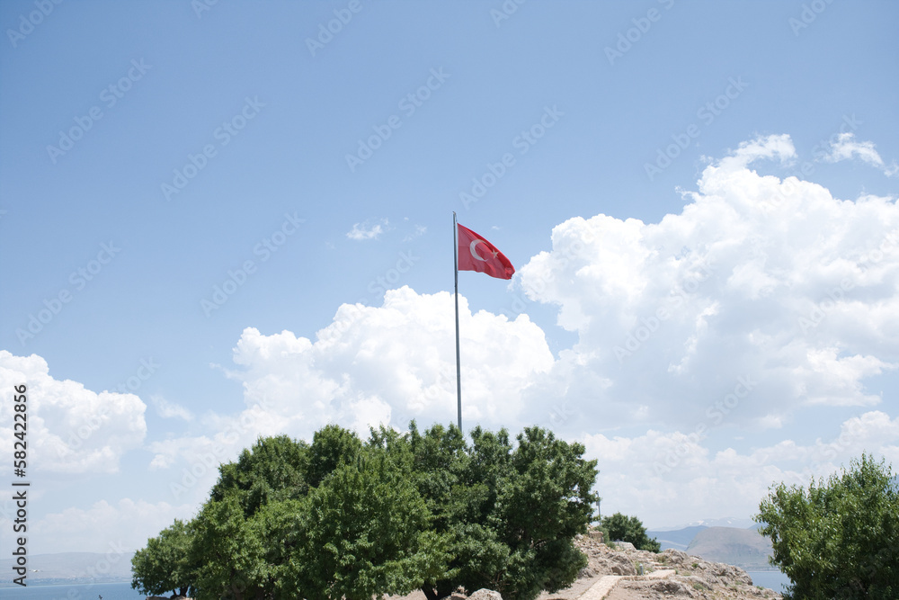 Turkish flag on the green hill, cloudy sky background