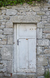 Port Louis, Bretagne, France : An old door with white paint that splits, embedded in an old grey stone wall