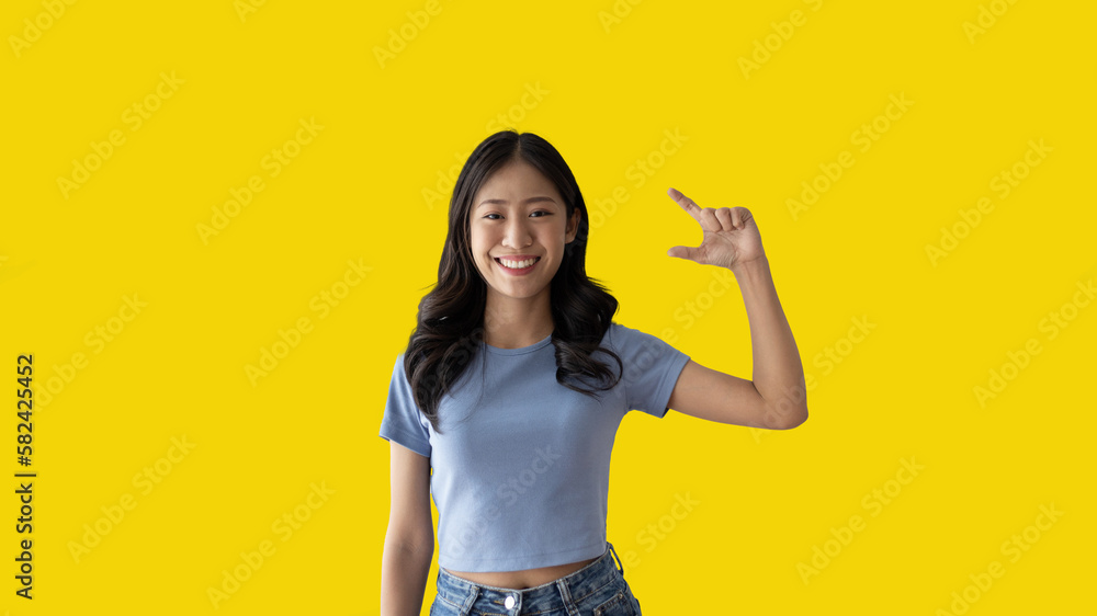 Asian woman with holding copyspace imaginary on the palm to insert an ad, Showing copyspace pointing, Showing her hand to present something on yellow background. Asian woman with holding copyspace imaginary on the palm to insert an ad, Showing copyspace pointing, Showing her hand to present something on yellow background.