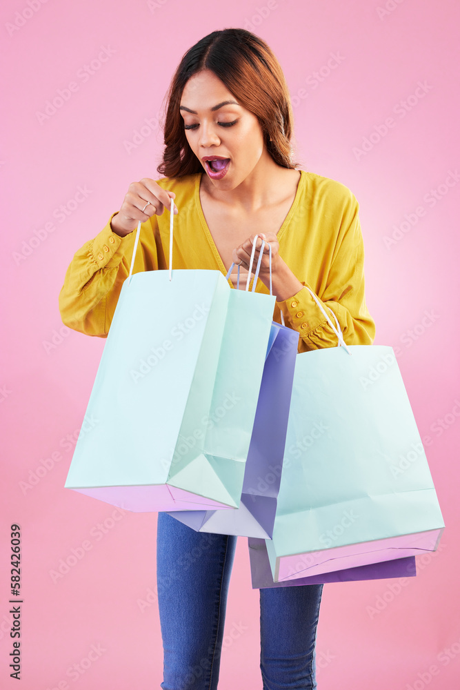 Woman, shopping bag and wow sale in studio with a customer happy about promotion or discount. Female model or shopper on a pink background for fashion, brand and gift or surprise in paper bags