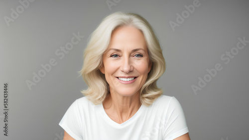 White mature woman with blond hair on grey empty background with copy space. Portrait. Generative AI © Dawid