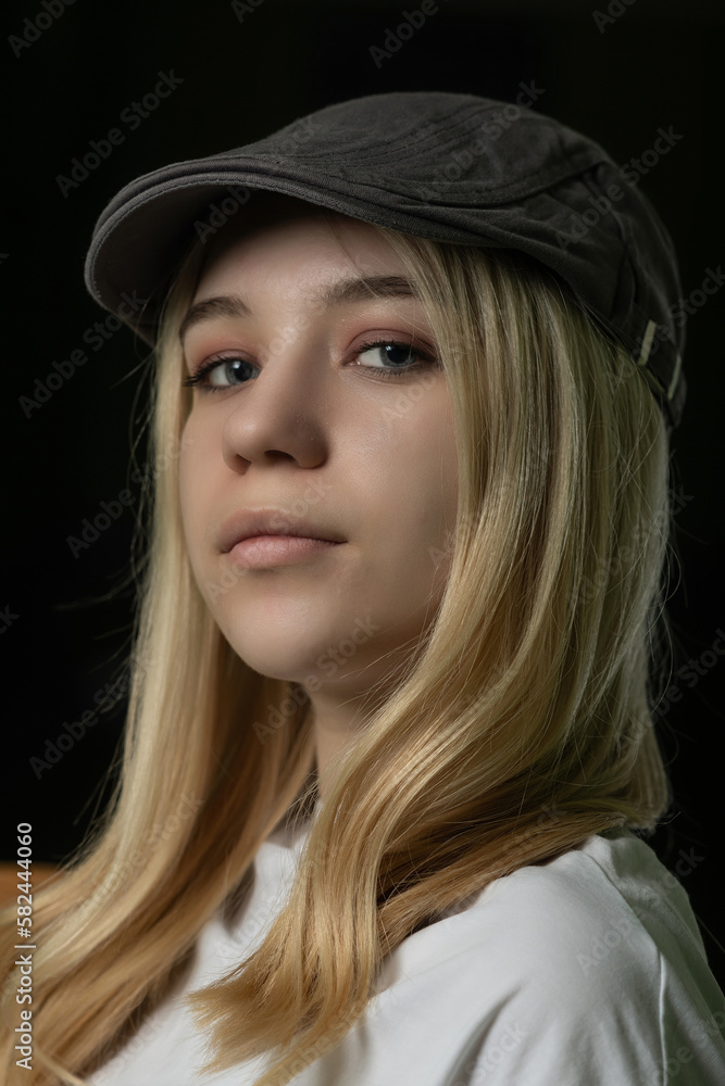Studio portrait of a young beautiful fair-haired girl in a white T-shirt and cap. Studio portrait of a young beautiful fair-haired girl in a white T-shirt and cap.