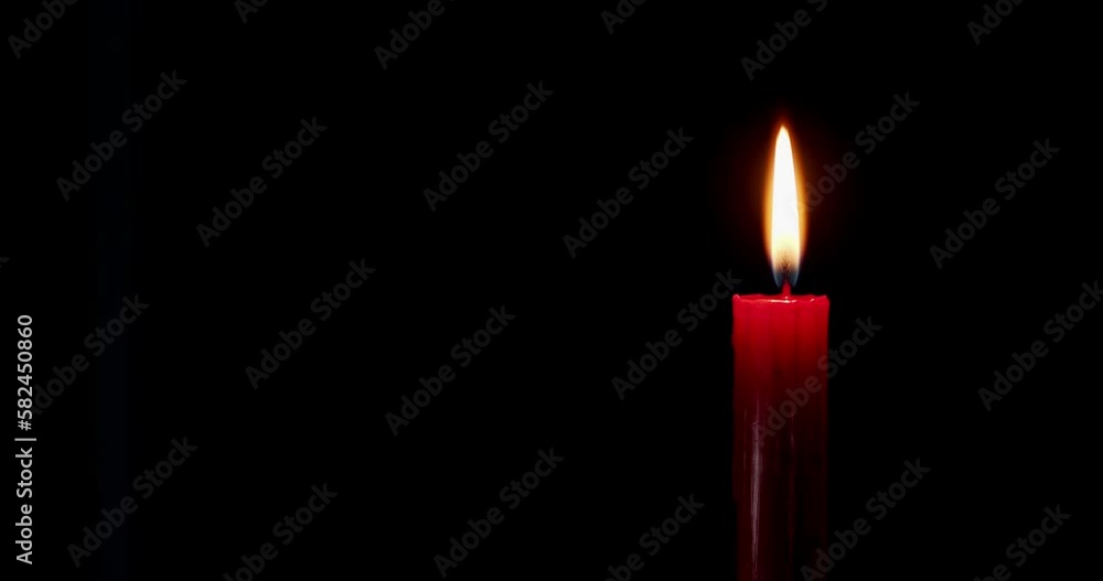 A single red candle burning. Isolated candle burning with dark background. Red paraffin candle with yellow shades burns on a black background. slow motion A single red candle burning. Isolated candle burning with dark background. Red paraffin candle with yellow shades burns on a black background. slow motion