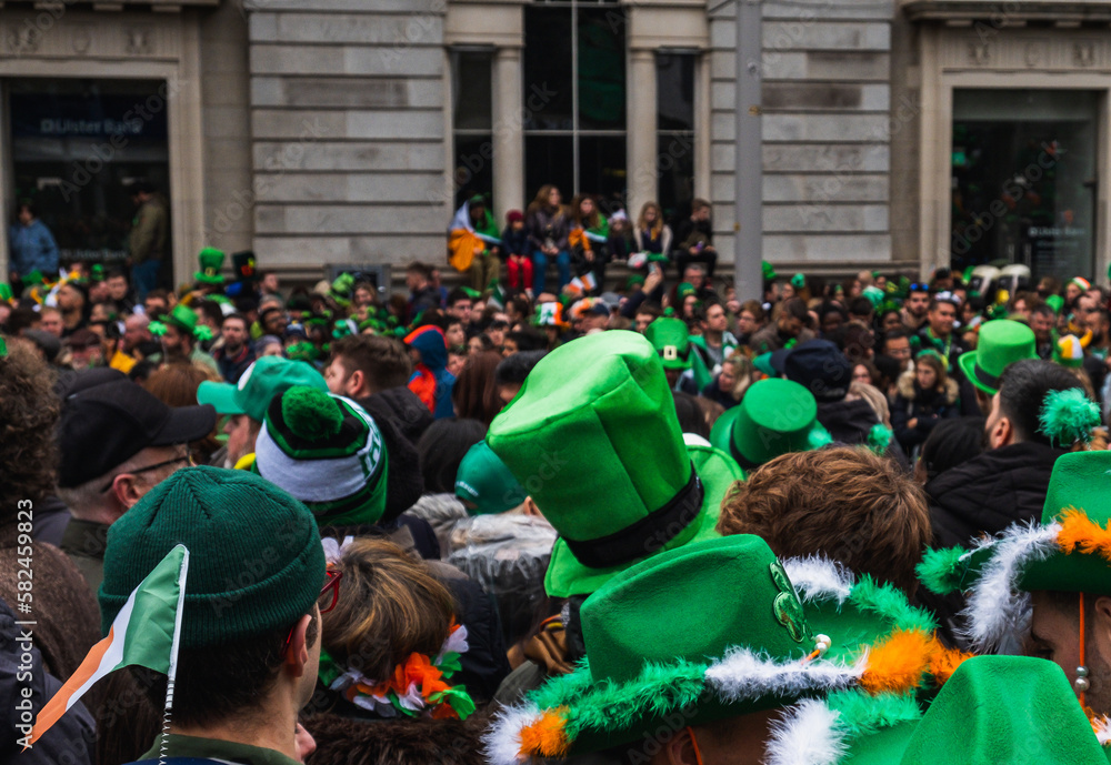 Naklejka premium Green hat in the crowd, people in the street with costumes, irish flag colours, Paddy's day parade in Dublin city, Ireland