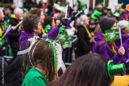 Girl with green clover headband, green outfit, crowd in green hats in background, watching the parade march in Dublin city center, Saint Patricks day, Ireland