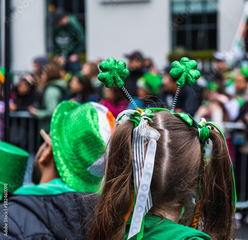 Girl with green clover headband, green outfit, crowd in green hats in background, watching the parade march in Dublin city center, Saint Patricks day, Ireland