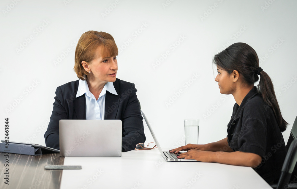 middle-aged business woman having a stern meeting with a female employee middle-aged business woman having a stern meeting with a female employee