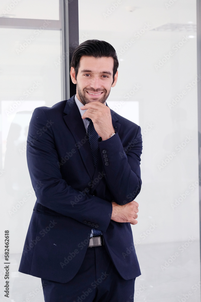Handsome young businessman in suit standing smiling inside office. Handsome young businessman in suit standing smiling inside office.