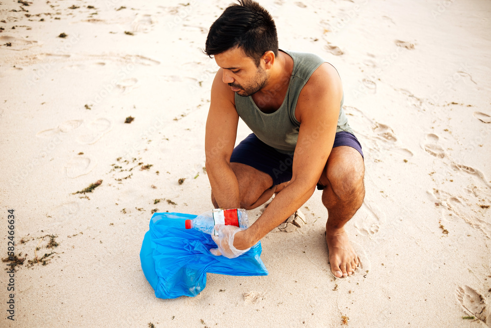 Volunteer man collecting trash on the beach. Ecology concept Volunteer man collecting trash on the beach. Ecology concept