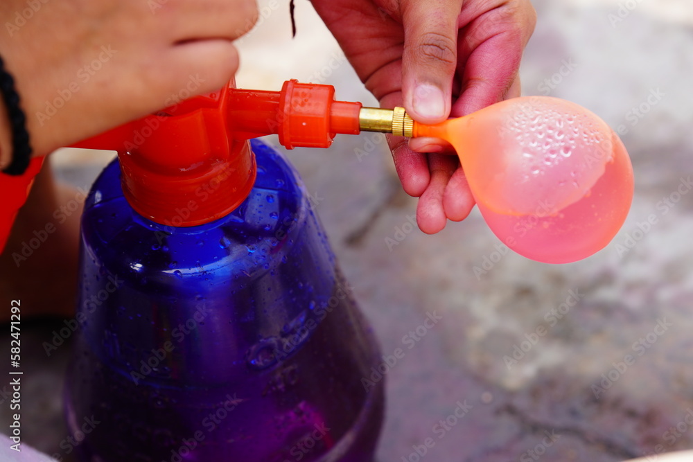 Naklejka premium someone filling water in the balloon for holi