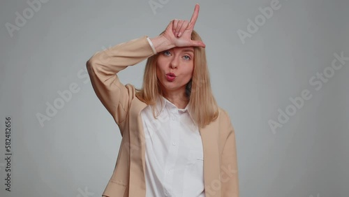 Business woman showing loser gesture and pointing on you, blaming accusing for unsuccess, expressing disrespect, mocking your failure, bullying abuse. Female girl in suit. Woman on gray background