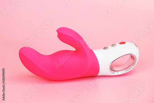 Waterproof adult sex toy from body-safe silicone on pink background. G-spot vibrator with clitoral stimulator from medical grade silicone. Bendy vibrator with clitoral stimulation arm