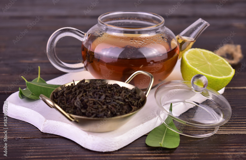 Tea in a transparent teapot on a white wooden board.
Tea in a transparent teapot on a white wooden board.