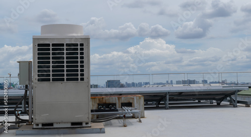 Air conditioner units (HVAC) on a roof of industrial building with blue sky.