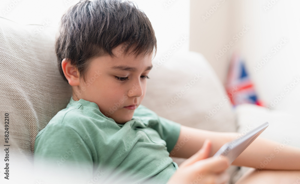 Education concept,School kid using tablet readying story from internet,Boy studying online learning at home,Child holding digital pad using wifi playing game or chatting with friends.Back to School Education concept,School kid using tablet readying story from internet,Boy studying online learning at home,Child holding digital pad using wifi playing game or chatting with friends.Back to School