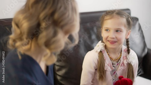 A female psychologist communicates with a child while playing with a doll. Clapping hands