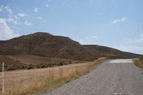 Road in a deserted area landscape with bare hills