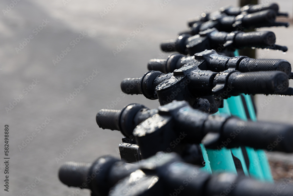 Wet handle bars of the electric scooters. Electric scooters standing in the rain on the street.