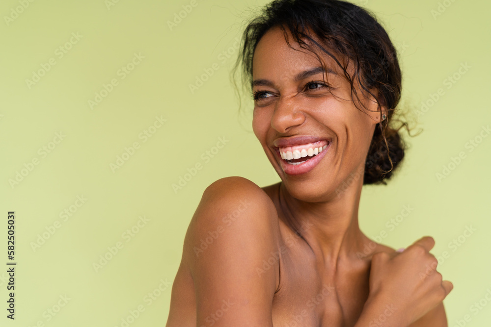 Obraz premium Beauty portrait of young topless african american woman with bare shoulders on green background with perfect skin and natural makeup