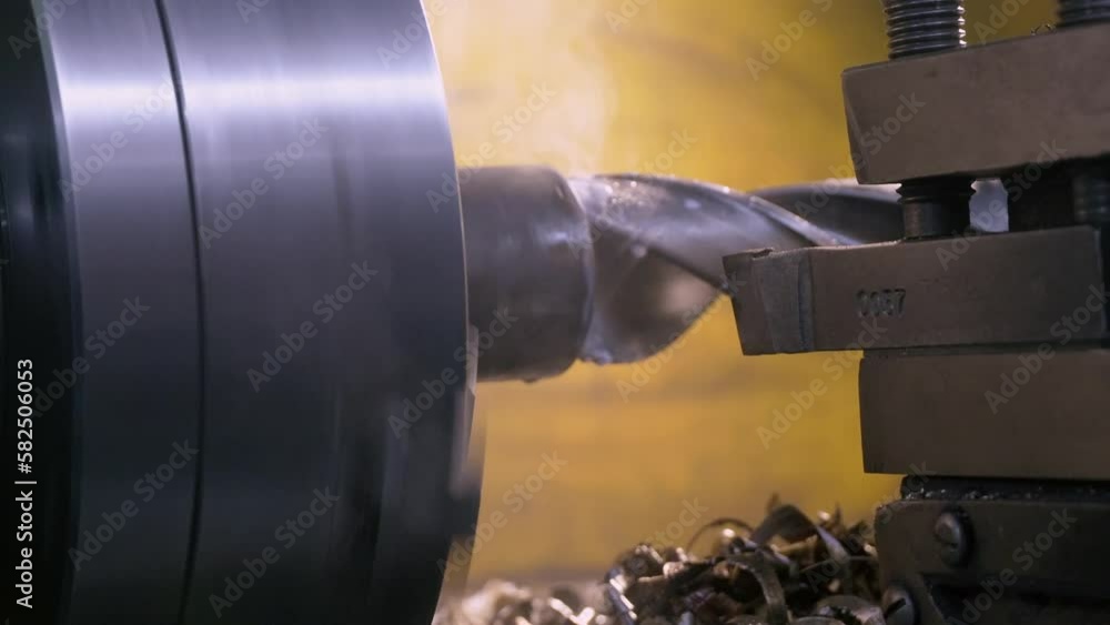 Drilling detail on lathe with metal shavings. Close-up of metallic workpiece clamped in rotating machine chuck. Steel drill bit. Heavy industry. Drilling detail on lathe with metal shavings. Close-up of metallic workpiece clamped in rotating machine chuck. Steel drill bit. Heavy industry.