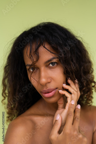 Beauty portrait of young topless african american woman with bare shoulders on green background with perfect skin and natural makeup