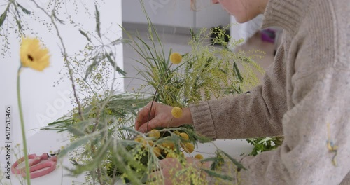 female doing new bouquet. Girl working in flower shop studio. Female florist artist cleans flowers for a beautiful bouquet, workplace view. High quality 4k footage