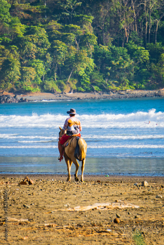 Costa Rican cowboy riding his horse on the beach in Jaco, Costa Rica 