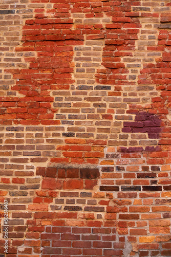  Vertical view of old wall with patches of different coloured bricks in irregular pattern