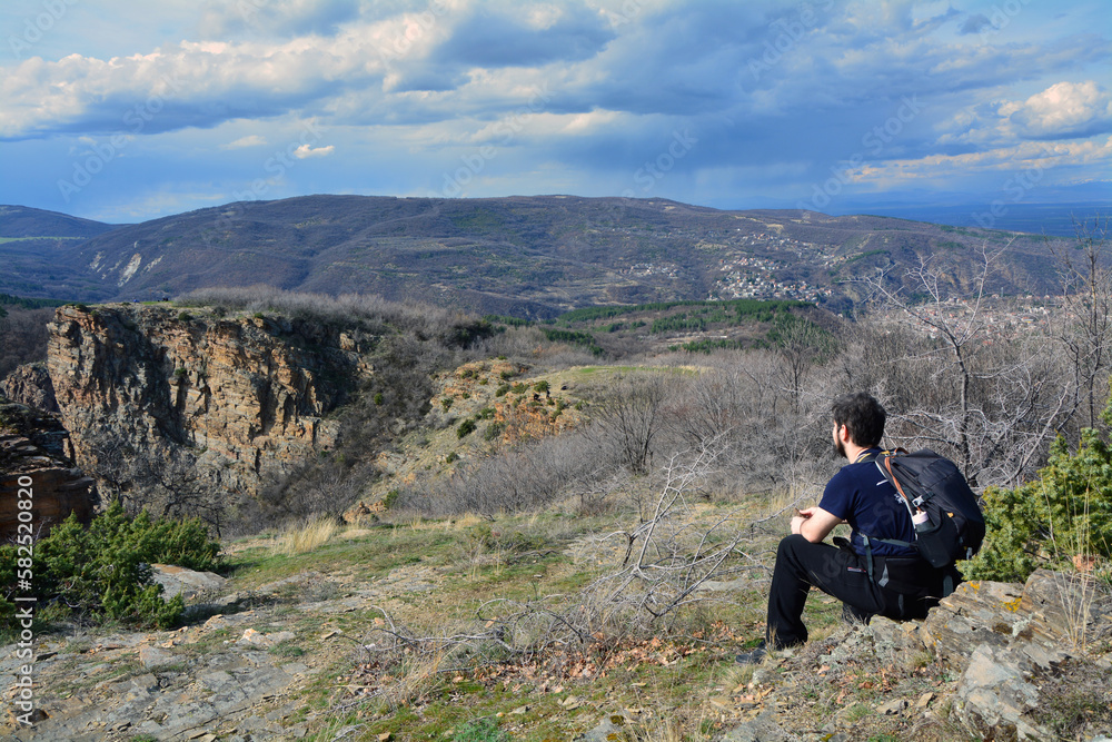 A man with a backpack sitting and staring at Momini scali near the village of Izvor A man with a backpack sitting and staring at Momini scali near the village of Izvor