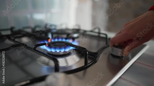 Woman turning on the gas burner on the stove.
