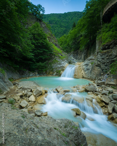 Turquoise forest river. Stream flowing through the trees