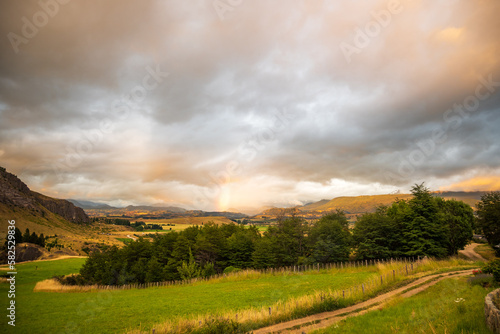 rainbow in a sunset over the hills of the valle simpson coyhaique, aysen region, patagonia, chile photo