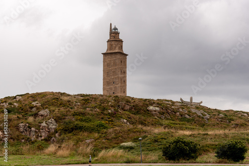 The Torre de Hercules, an ancient Roman lighthouse and a symbol of La Coruña, Galicia, Spain, stands tall against the blue sky, offering a glimpse into the region's rich history and culture © MartinOscar