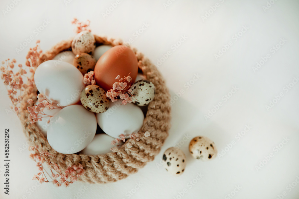 Easter white and brown eggs in a basket with flowers on a white background Easter white and brown eggs in a basket with flowers on a white background