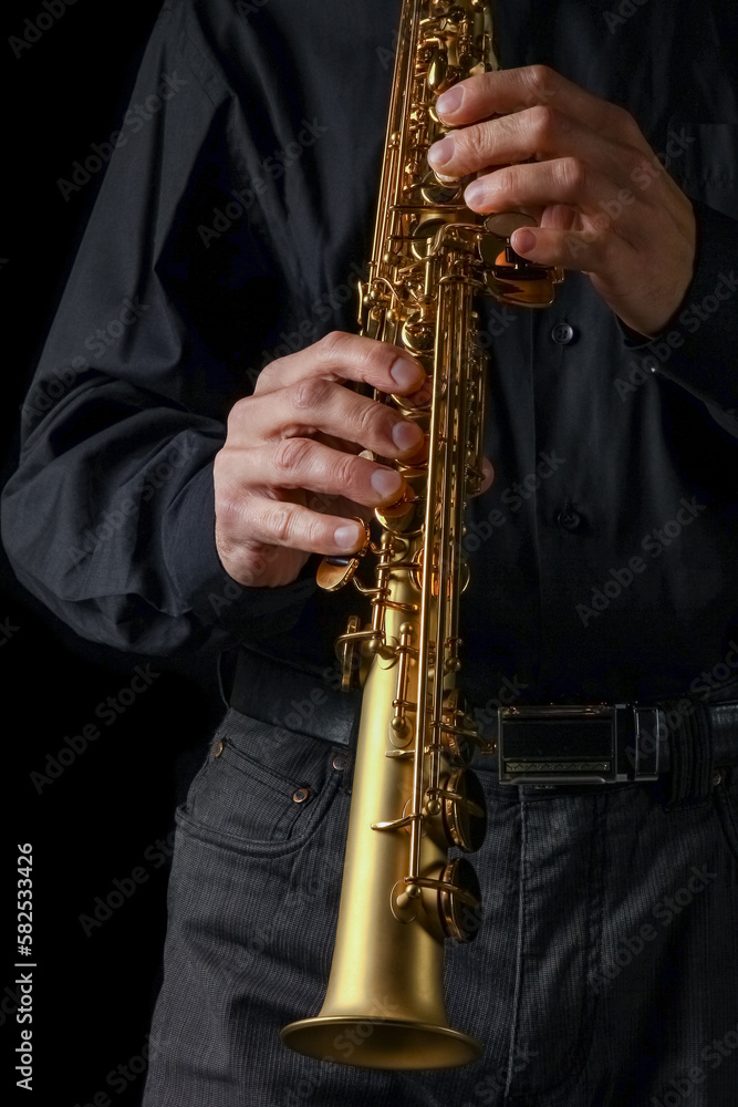Naklejka premium soprano saxophone in hands on a black background