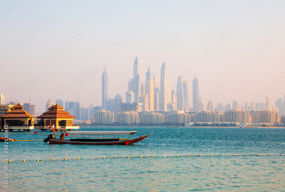 Fototapeta premium Dubai, UAE. Tourists boat at Palm Jumeirah and Dubai marina at the background at sunset