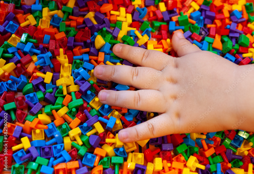 A child plays with a multi-colored mosaic, his hand rests on small plastic parts.