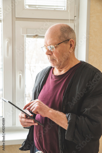 An old man using a tablet. Concept Elderly