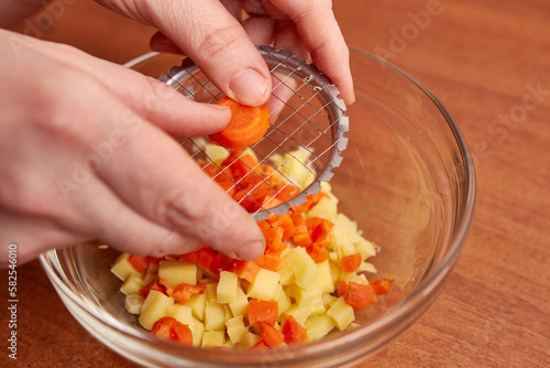 Using a hand slicer, carrots are chopped for salad preparation.