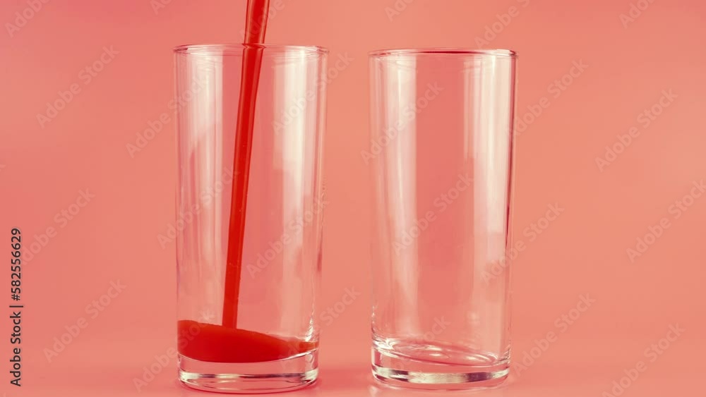Tomato juice is poured into glass goblets on a pink background. Slow motion. Tomato juice is poured into glass goblets on a pink background. Slow motion.